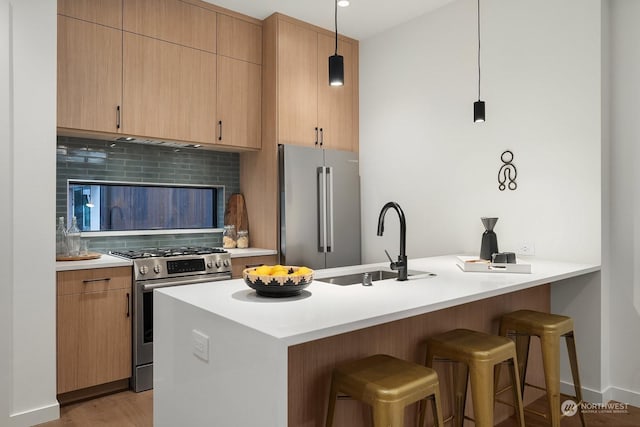 kitchen featuring sink, hanging light fixtures, premium appliances, light brown cabinetry, and a breakfast bar