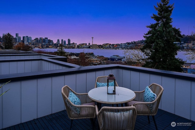 balcony at dusk featuring a water view