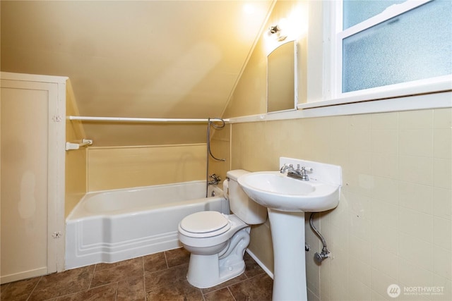 bathroom featuring tile patterned flooring, toilet, a sink, vaulted ceiling, and tub / shower combination