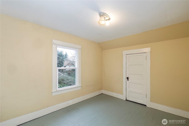 spare room with wood-type flooring, baseboards, and vaulted ceiling