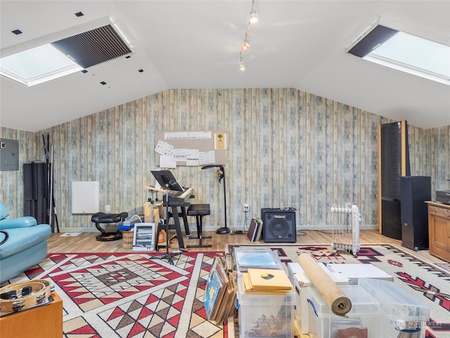 living room featuring rail lighting, vaulted ceiling with skylight, electric panel, and light hardwood / wood-style flooring