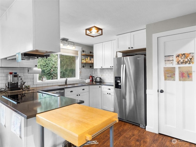 kitchen featuring white cabinetry, sink, backsplash, and stainless steel fridge