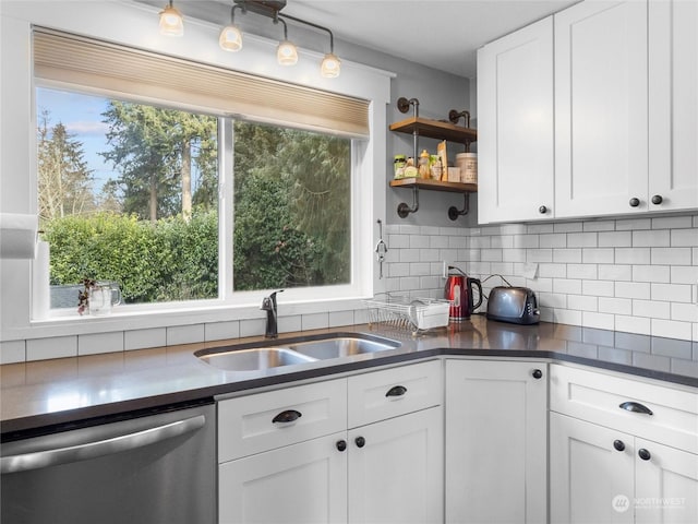 kitchen with tasteful backsplash, sink, stainless steel dishwasher, and white cabinets