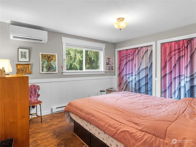 bedroom featuring a baseboard heating unit, dark wood-type flooring, and a wall mounted AC