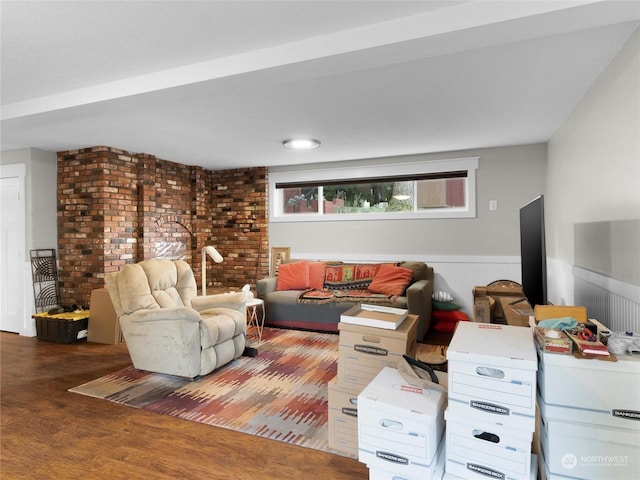 living room featuring hardwood / wood-style flooring and brick wall