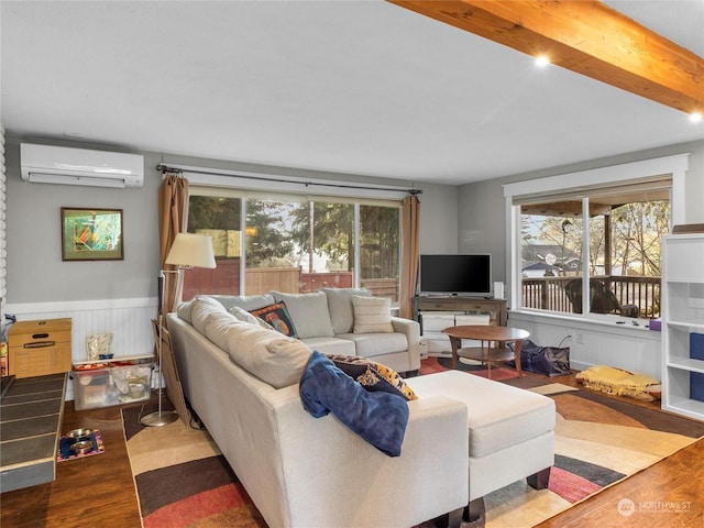 living room featuring hardwood / wood-style floors, a wall mounted air conditioner, and beam ceiling