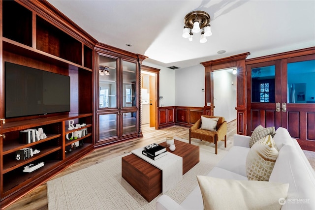 living room with built in shelves and light hardwood / wood-style flooring