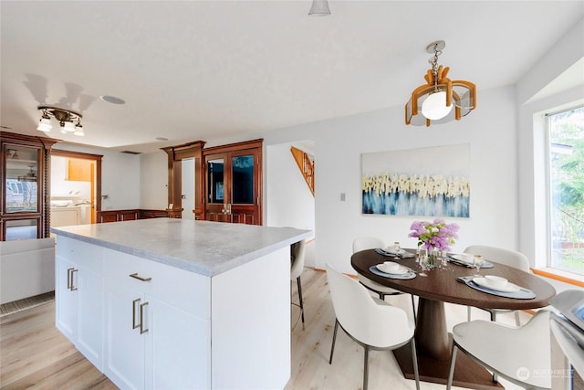 kitchen featuring hanging light fixtures, a center island, white cabinets, light hardwood / wood-style flooring, and washing machine and clothes dryer