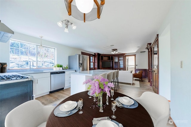 dining area with sink, ceiling fan, and light wood-type flooring