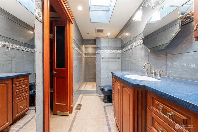 bathroom featuring tile walls, tile patterned flooring, a skylight, and vanity