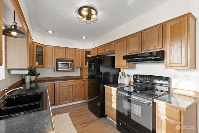 kitchen featuring a textured ceiling, light hardwood / wood-style flooring, hanging light fixtures, black appliances, and sink