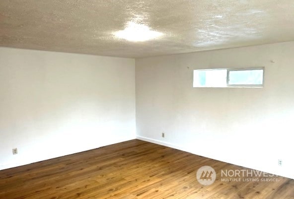 unfurnished room with hardwood / wood-style flooring and a textured ceiling