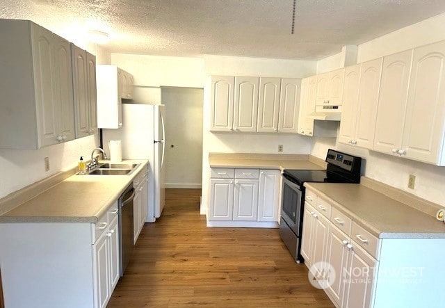 kitchen with sink, wood-type flooring, white cabinets, and appliances with stainless steel finishes