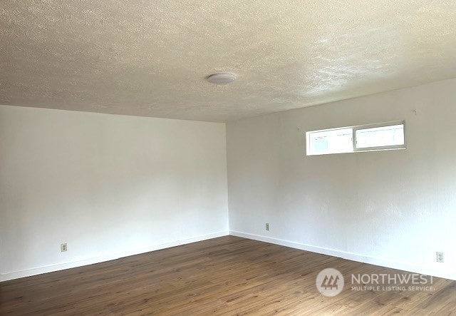 empty room with dark wood-type flooring and a textured ceiling