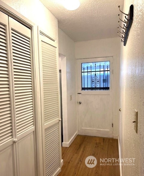 corridor with a textured ceiling and light wood-type flooring