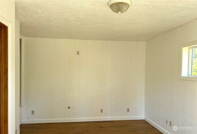 empty room featuring dark hardwood / wood-style flooring and a textured ceiling