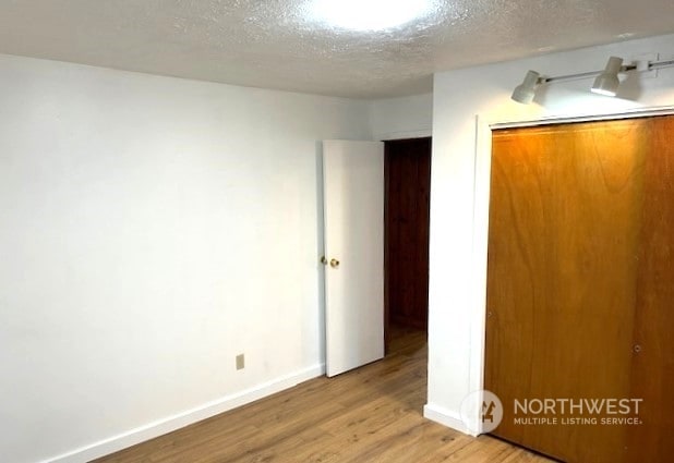 unfurnished bedroom with a closet, light hardwood / wood-style floors, and a textured ceiling