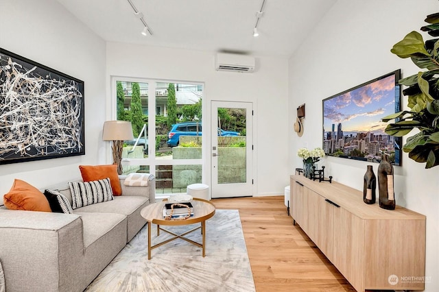 living room with light wood-type flooring, rail lighting, and a wall mounted air conditioner