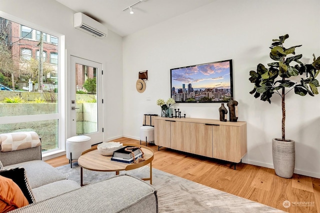 living room featuring light hardwood / wood-style floors, a wall mounted air conditioner, and rail lighting