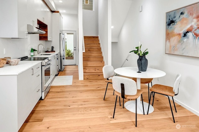 kitchen with white cabinets, light wood-type flooring, appliances with stainless steel finishes, and sink