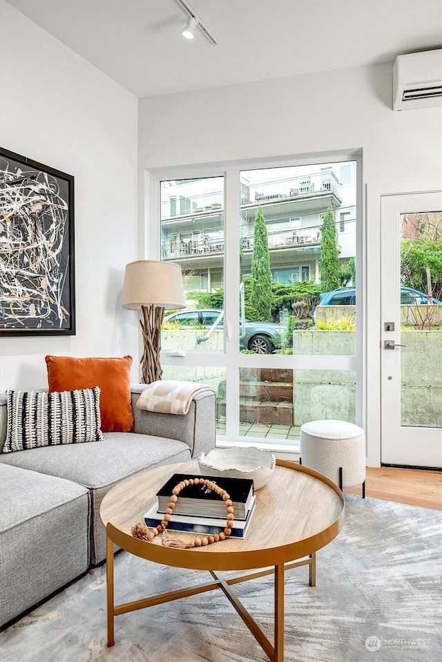 interior space featuring an AC wall unit, rail lighting, and wood-type flooring