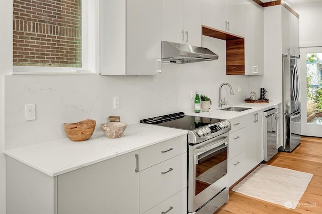 kitchen featuring white cabinets, light hardwood / wood-style floors, stainless steel appliances, light stone counters, and sink