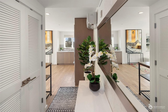 hallway with light hardwood / wood-style floors and a wall mounted AC