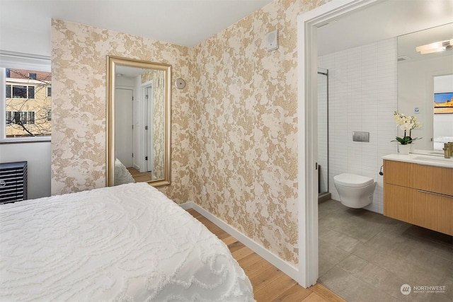 bedroom featuring sink, ensuite bath, and light wood-type flooring