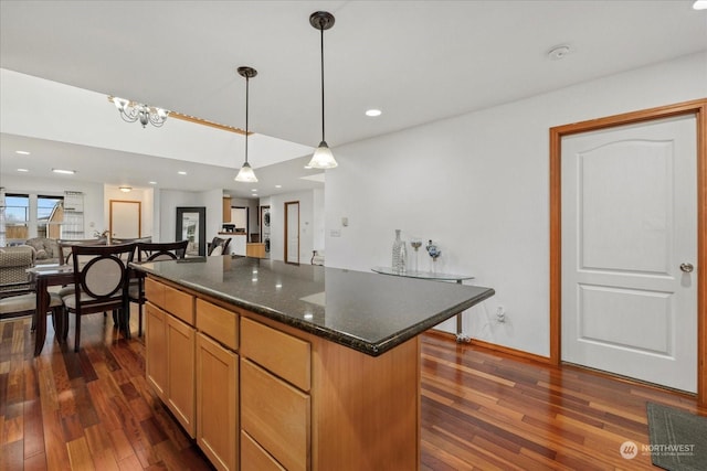 kitchen with pendant lighting, dark stone countertops, a center island, and dark wood-type flooring