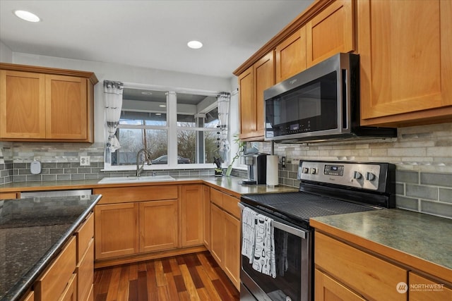 kitchen featuring appliances with stainless steel finishes, backsplash, dark hardwood / wood-style flooring, and sink