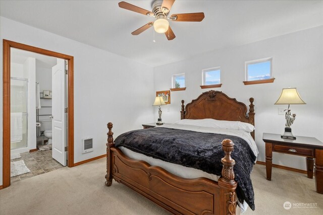 bedroom with ceiling fan, light carpet, and ensuite bath