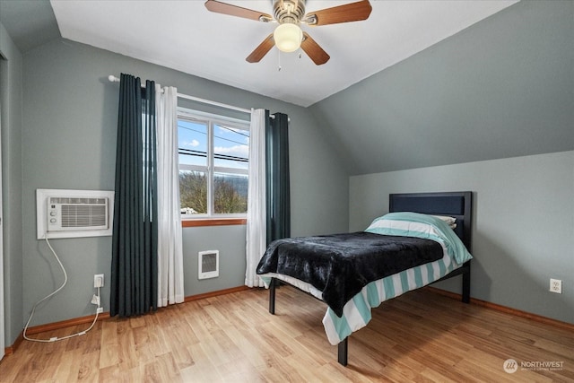 bedroom with a wall unit AC, lofted ceiling, ceiling fan, and light hardwood / wood-style floors