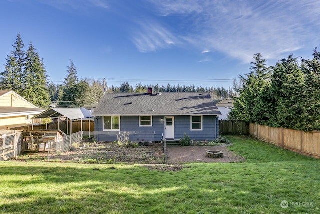 rear view of property with a yard and an outdoor fire pit