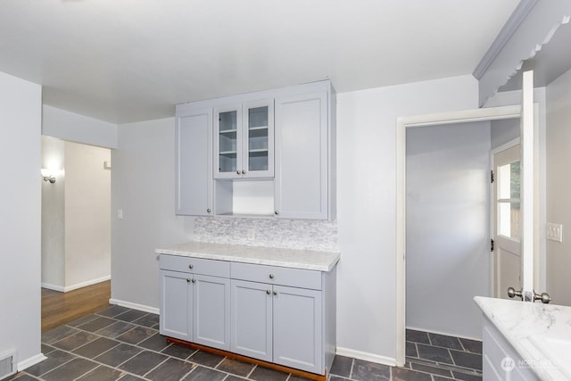 kitchen featuring gray cabinets, light stone counters, and tasteful backsplash