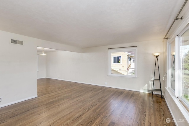 unfurnished room featuring plenty of natural light and dark hardwood / wood-style floors