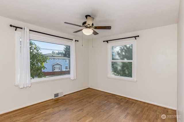 empty room with wood-type flooring, a wealth of natural light, and ceiling fan