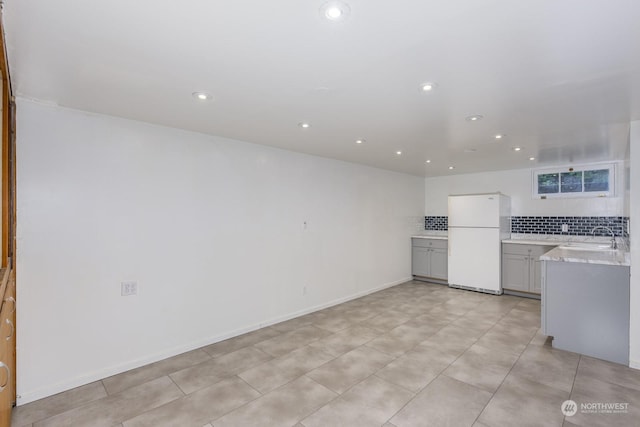 kitchen featuring backsplash, sink, and white refrigerator