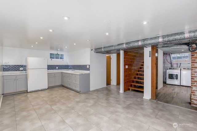 kitchen with backsplash, white refrigerator, sink, gray cabinets, and independent washer and dryer