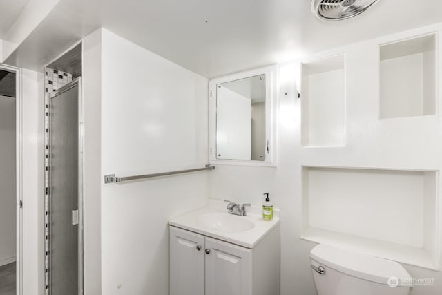 bathroom featuring vanity, toilet, and a shower with door