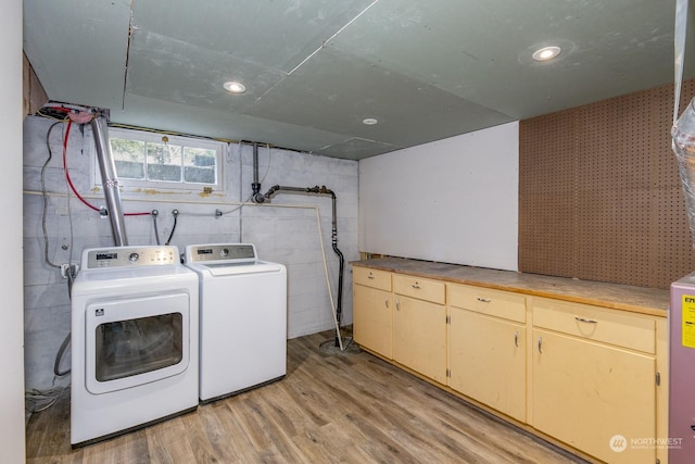 laundry area with cabinets, light wood-type flooring, and separate washer and dryer