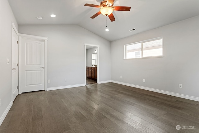 unfurnished bedroom featuring ceiling fan, ensuite bathroom, dark wood-type flooring, and vaulted ceiling