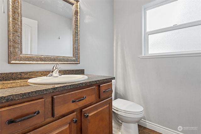 bathroom with toilet, vanity, and tile patterned flooring