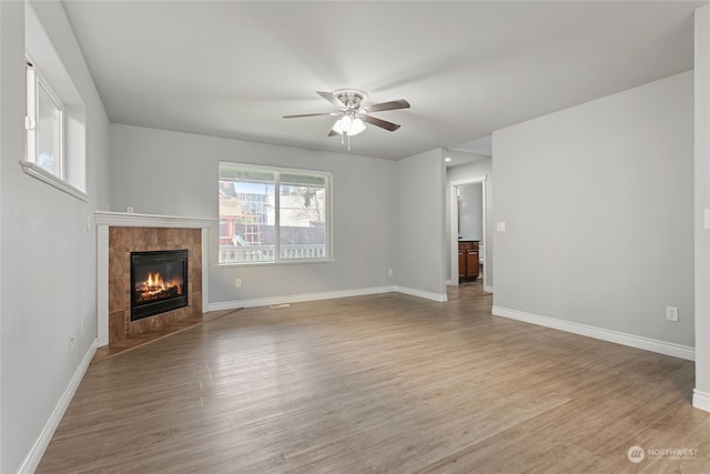 unfurnished living room featuring a fireplace, light hardwood / wood-style floors, and ceiling fan