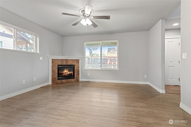 unfurnished living room with light hardwood / wood-style floors, plenty of natural light, ceiling fan, and a fireplace