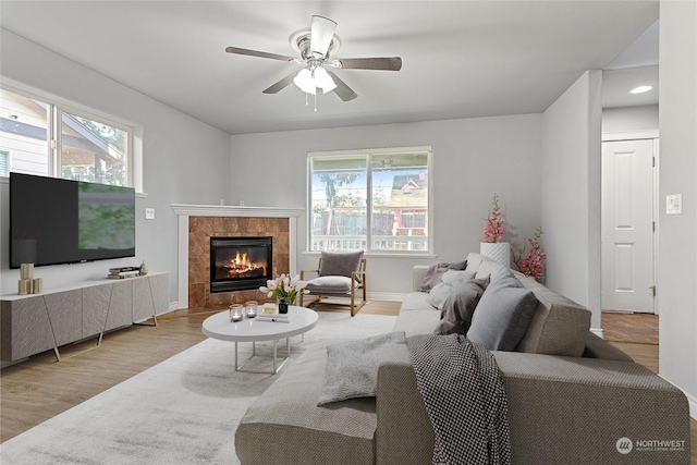 living room featuring light hardwood / wood-style floors, ceiling fan, and a fireplace