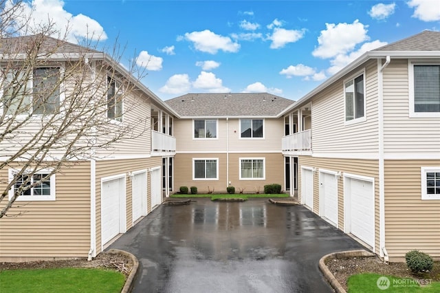 view of property exterior with a garage, a balcony, and driveway