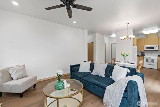 living area featuring recessed lighting, wood finished floors, and ceiling fan with notable chandelier