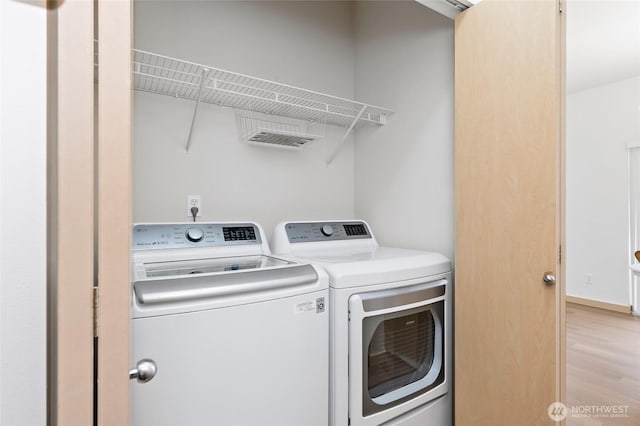 clothes washing area featuring light wood finished floors, laundry area, and washer and clothes dryer