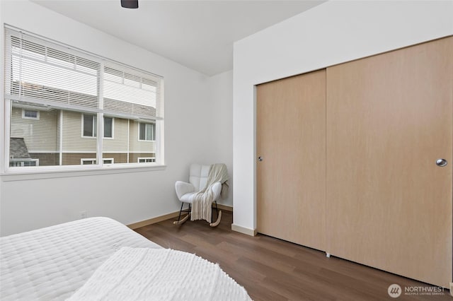 bedroom with ceiling fan, wood finished floors, a closet, and baseboards