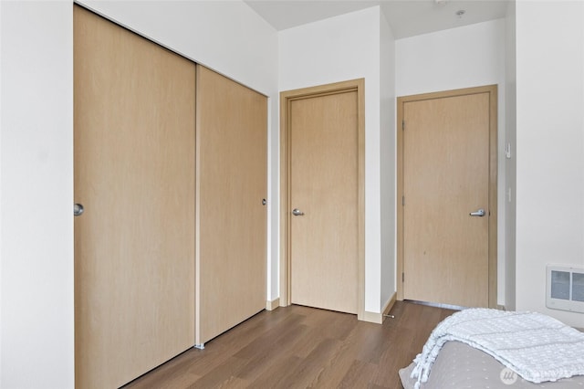 bedroom with heating unit and wood finished floors